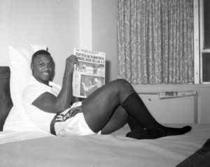 Joe Frazier reads a newspaper on a bed